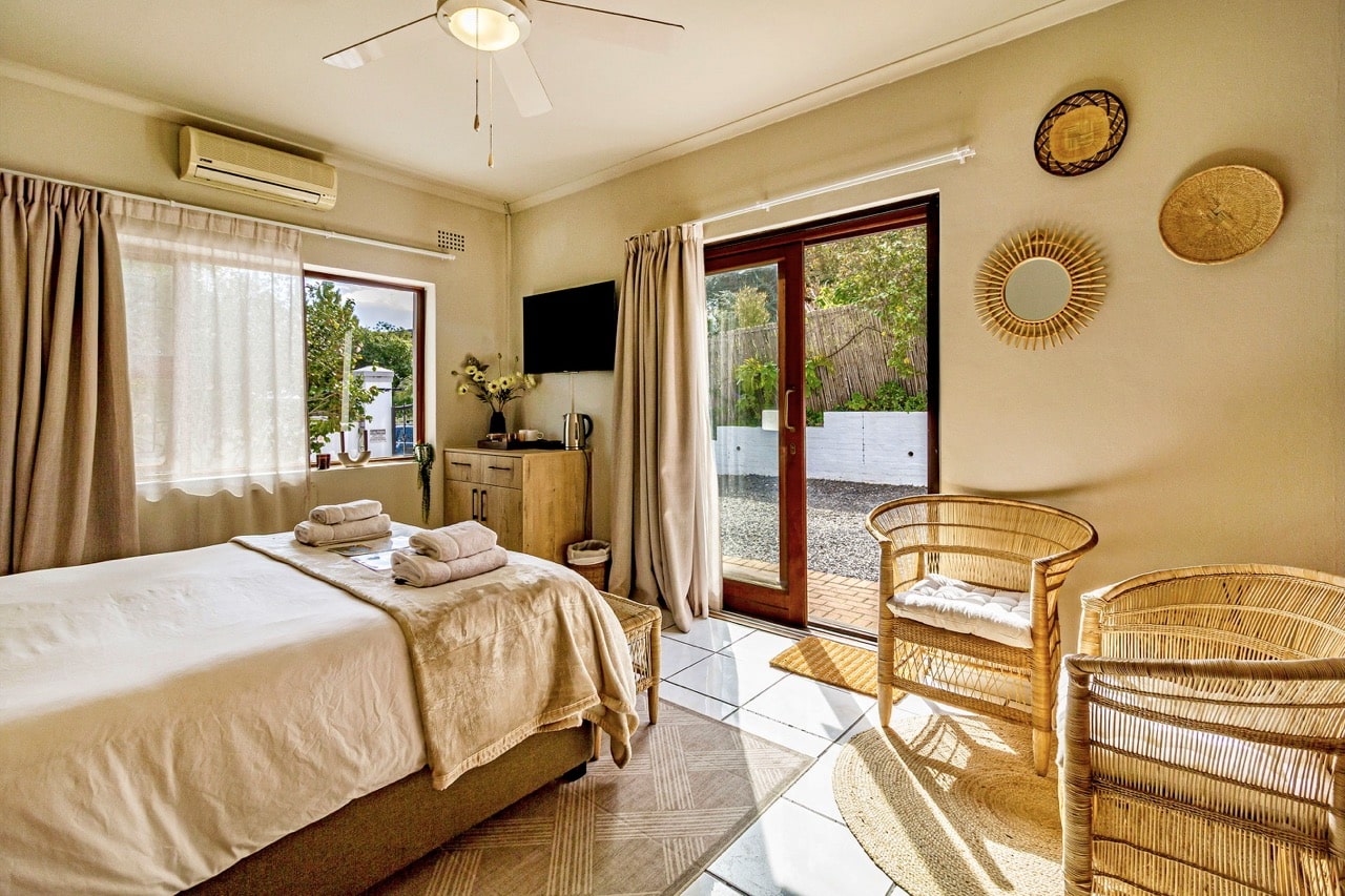 The African Suite: a bright bedroom with rattan chairs and sliding doors
