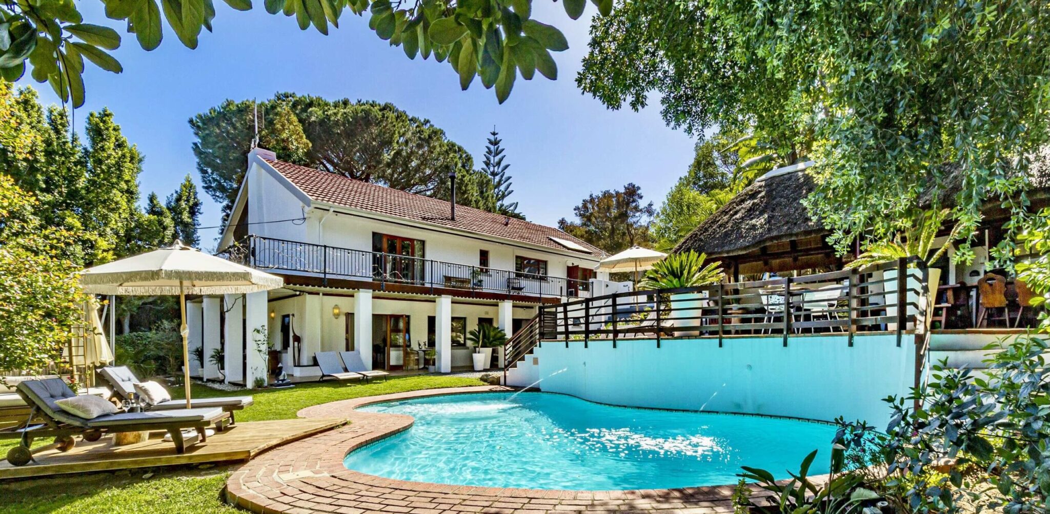 The villa with its pool, sun loungers and thatched lapa