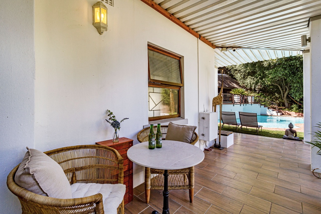 Die überdachte Veranda von Garden Room 1 mit Blick auf Pool und Liegen
