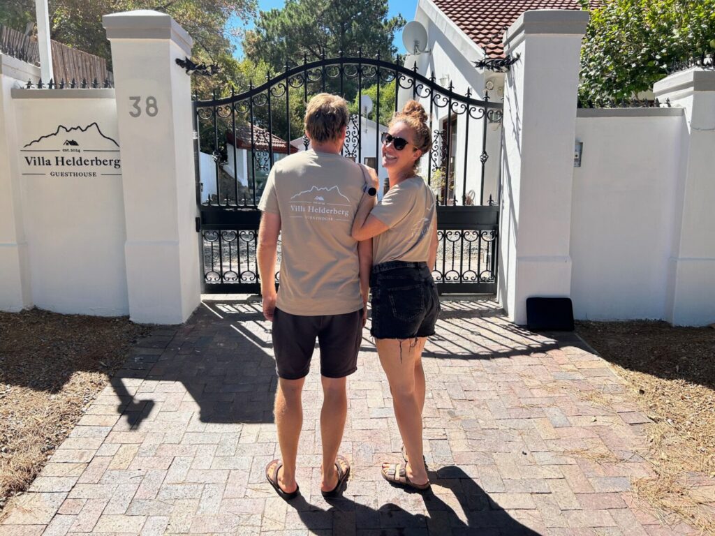 Two people at a white gate with flowers