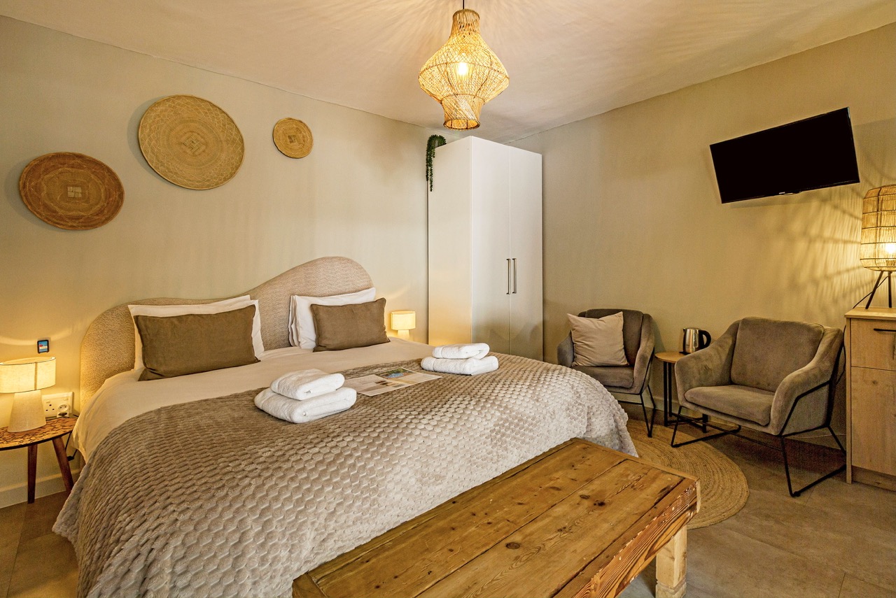 Pool Suite 1: das Bett mit geflochtenen Wandkörben und einem Lesesessel
