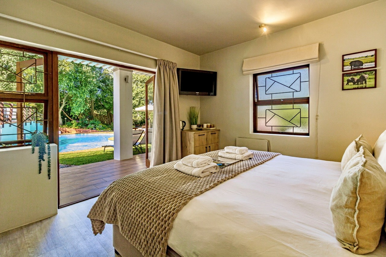 Pool Suite 2: das Bett mit offenen Türen zu Pool und Garten